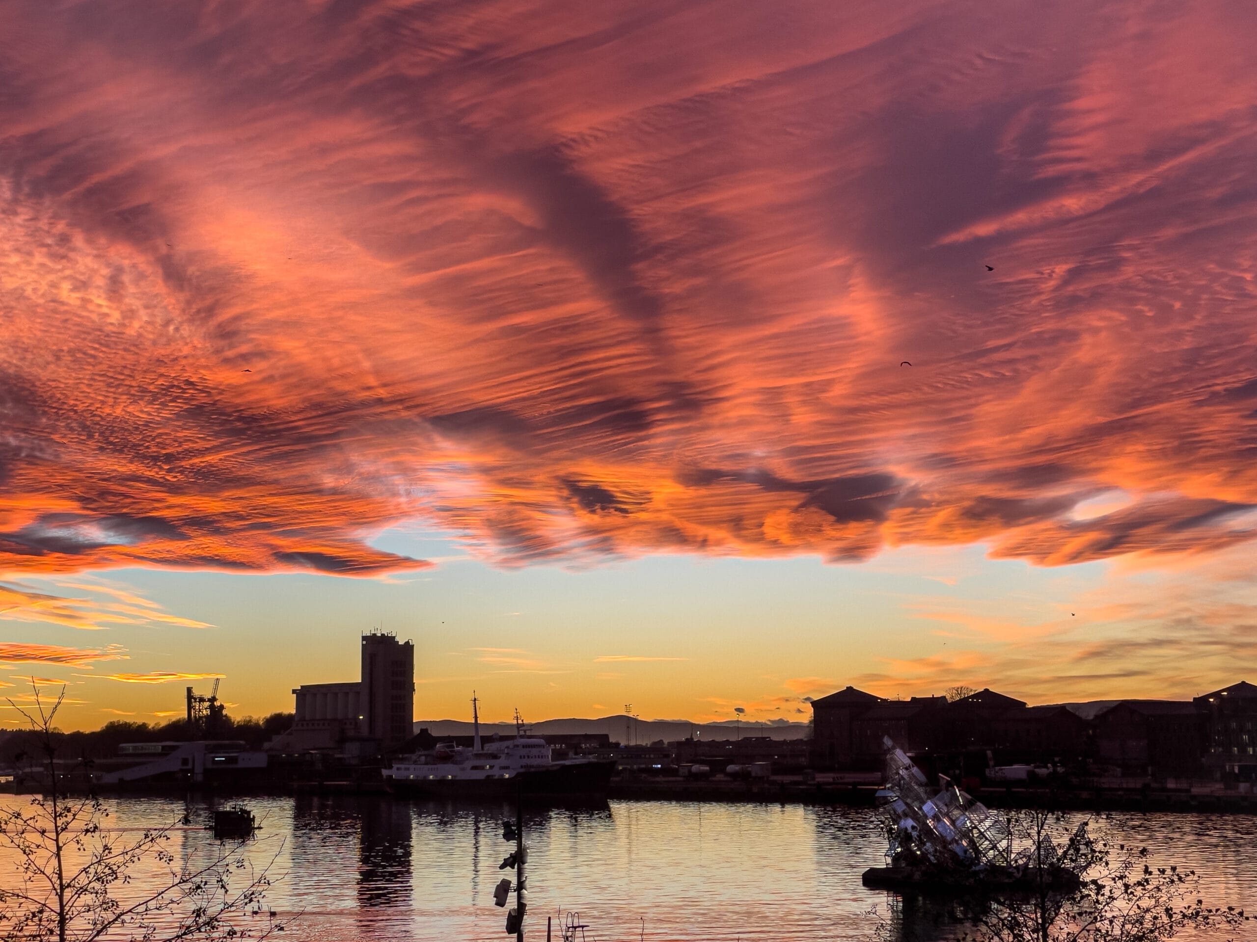 Dramatic orange sunset over harbour and city skyline