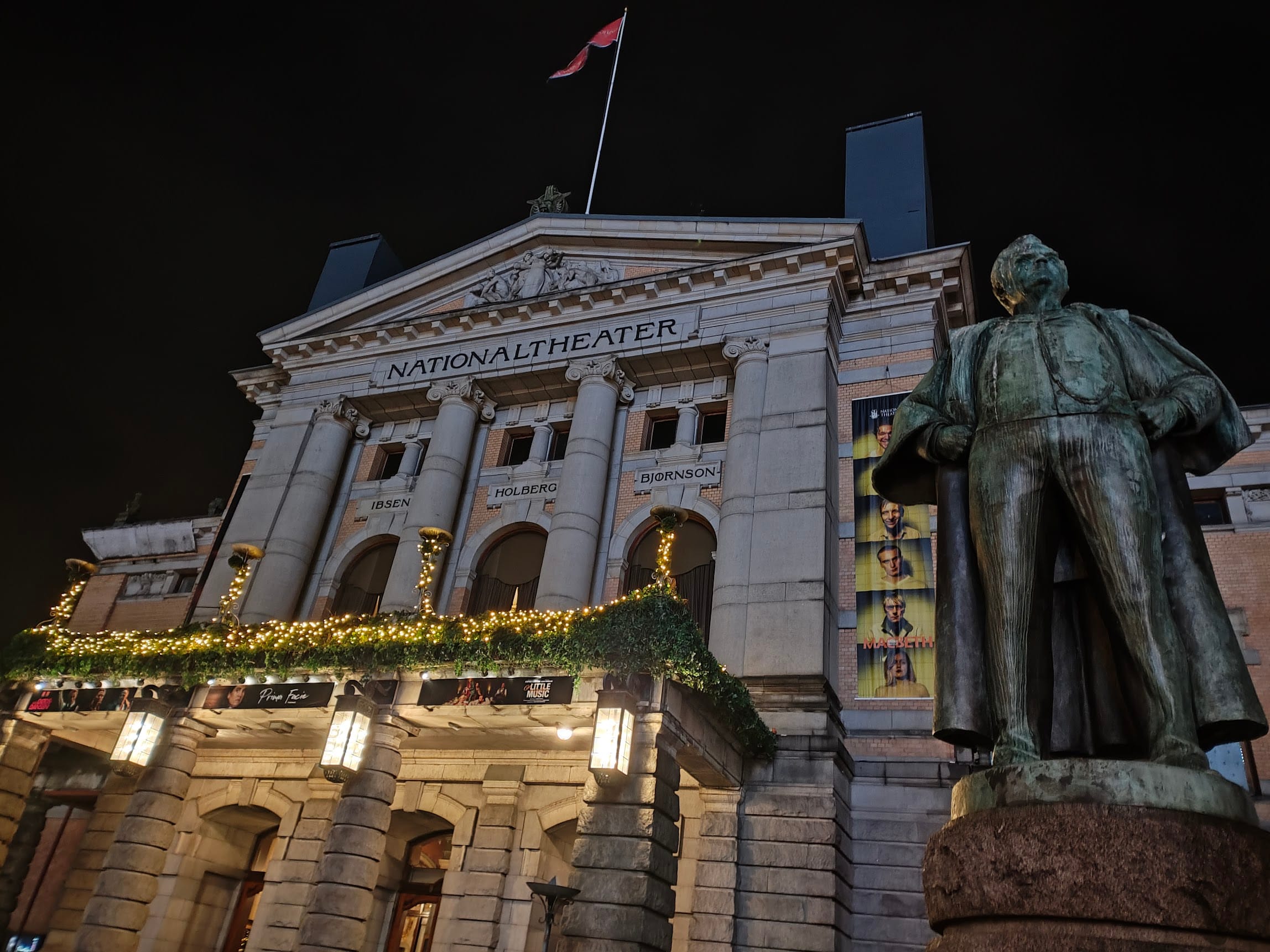 National Theatre building at night with statue