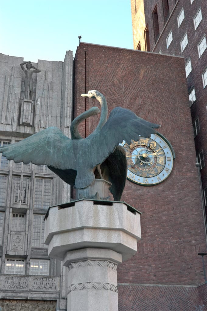 Bronze swan statue before brick building and clock