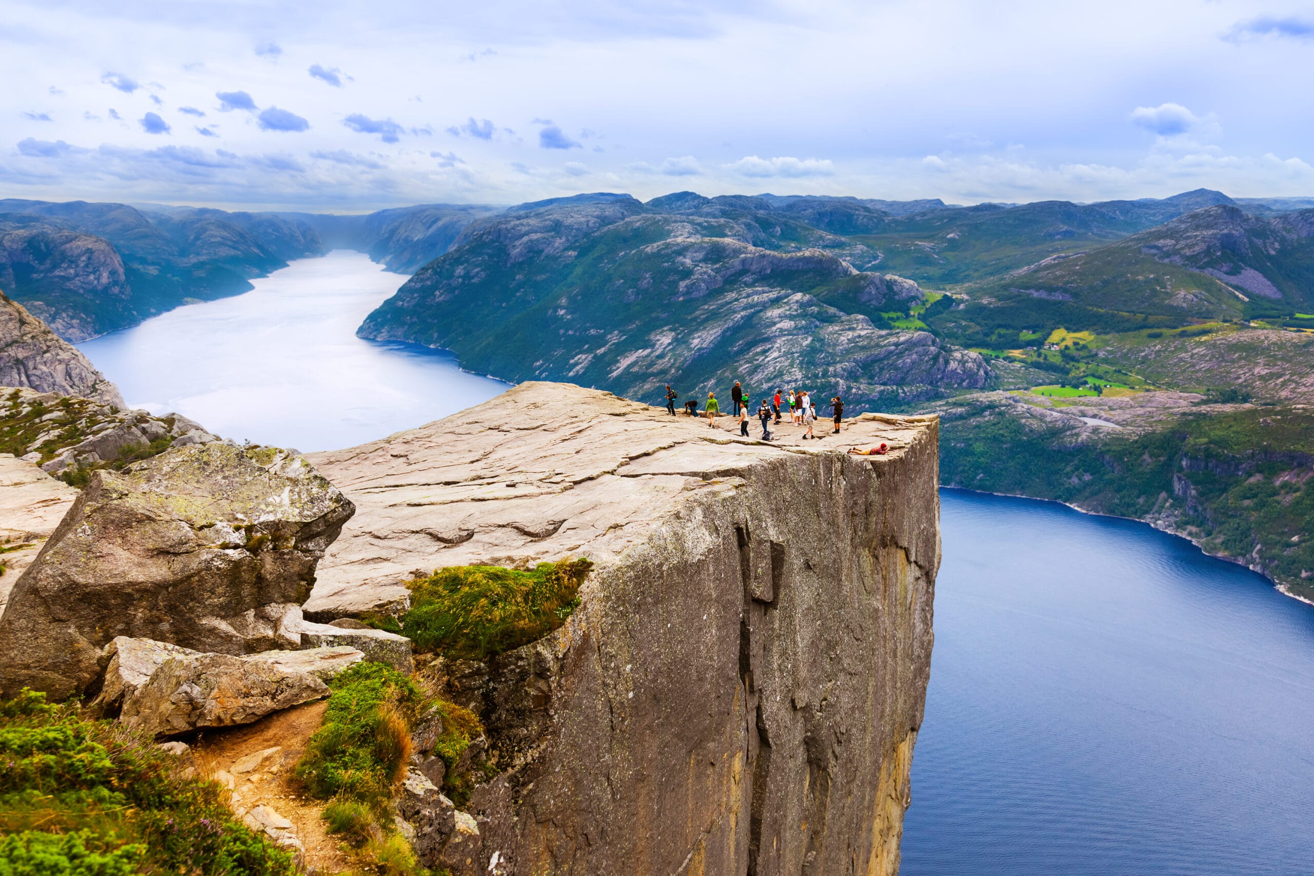 Hikers on cliff above Norwegian fjord