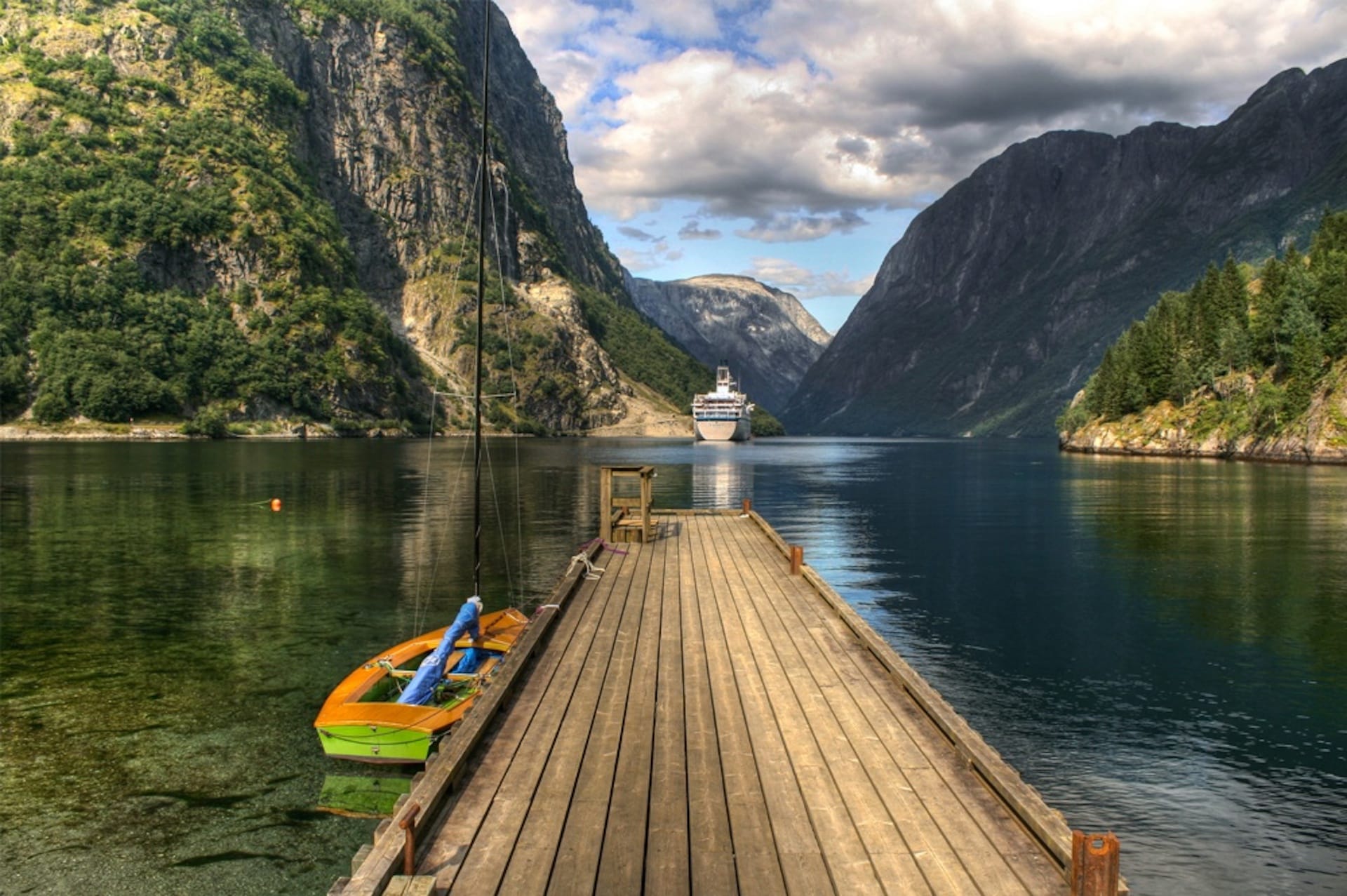 Wooden pier overlooking fjord with distant cruise ship