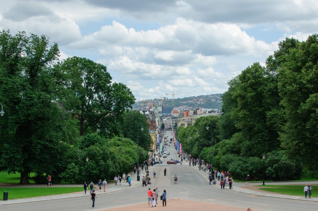 Tree-lined city boulevard with pedestrians and skyline