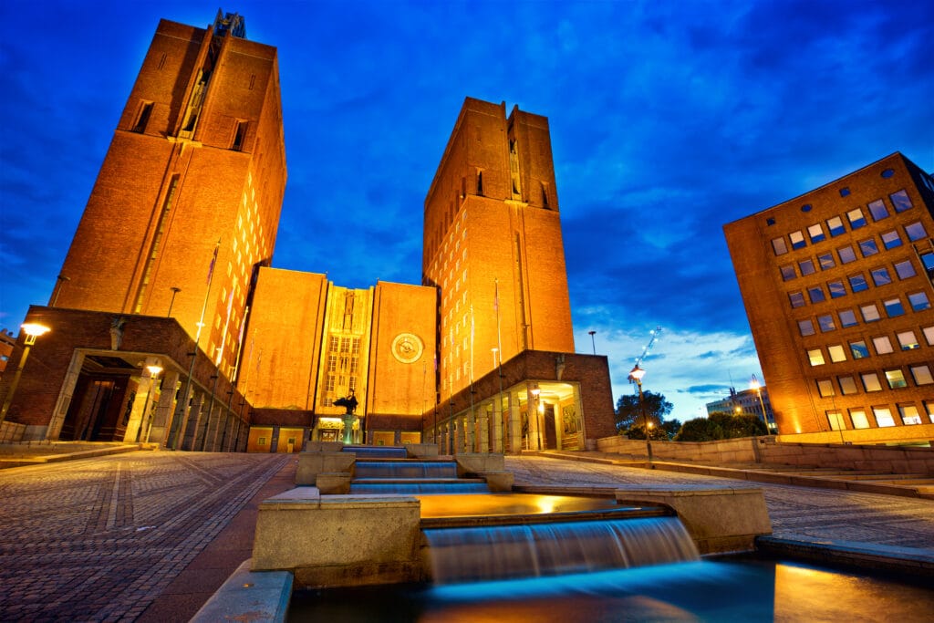 Oslo City Hall illuminated at dusk with fountain