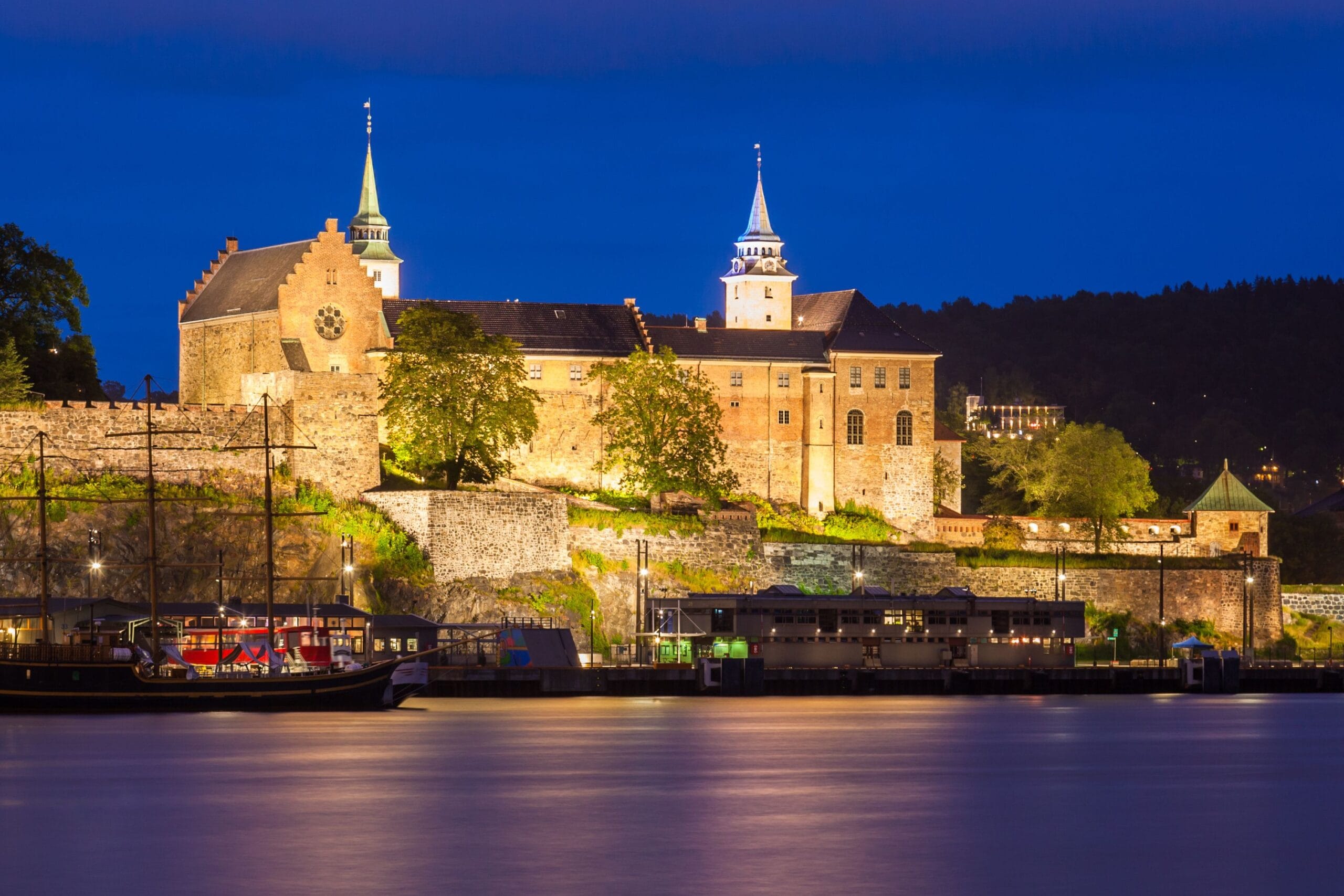 Illuminated historic fortress overlooking river at night