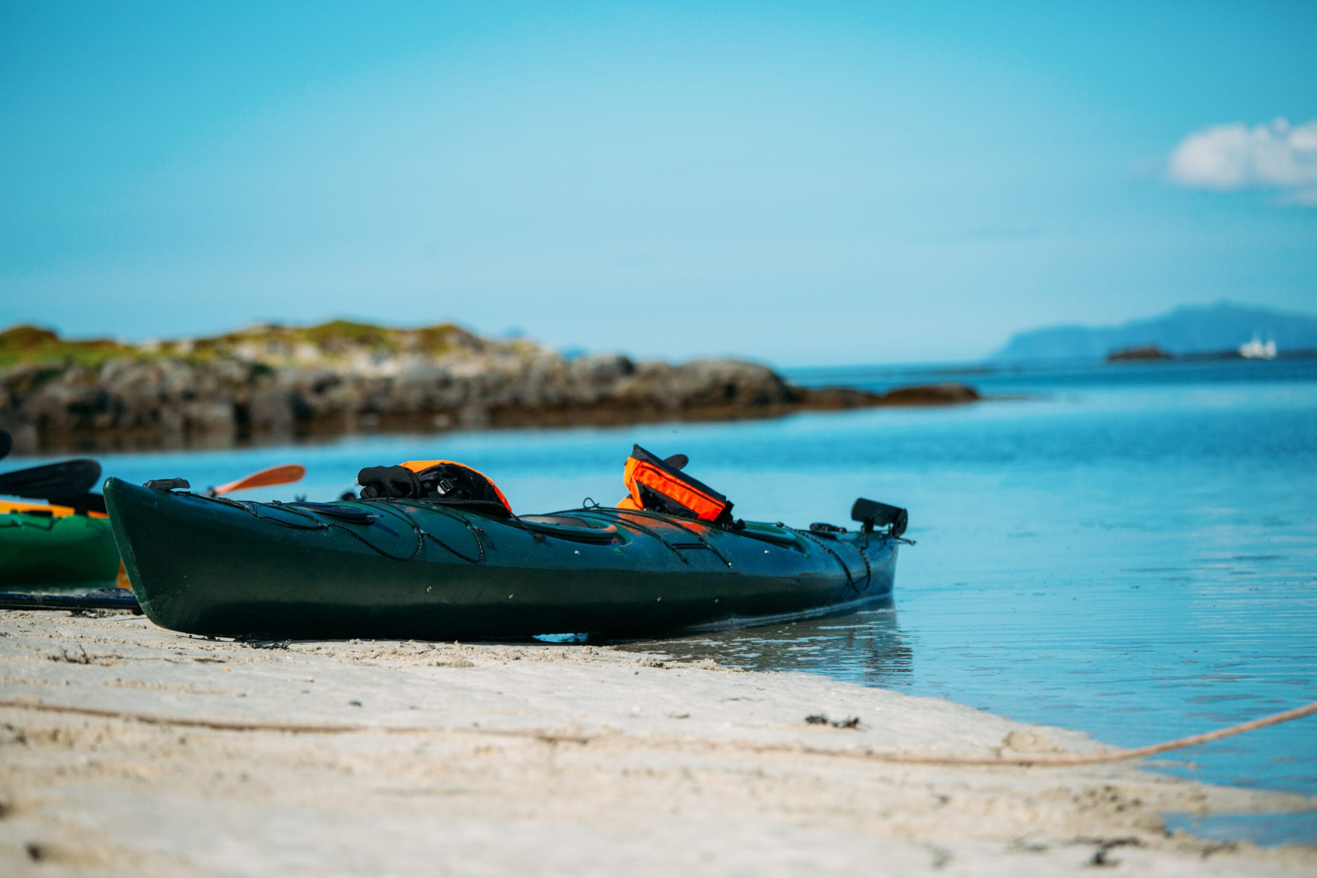 Kayak resting on sandy beach by calm sea