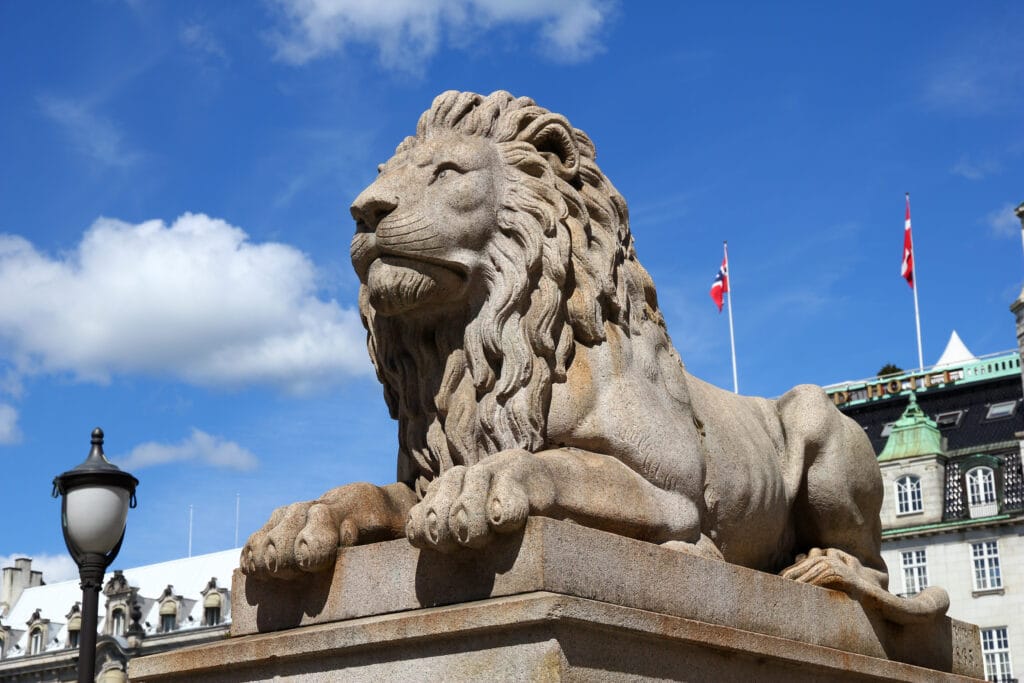 Stone lion statue on pedestal under blue sky